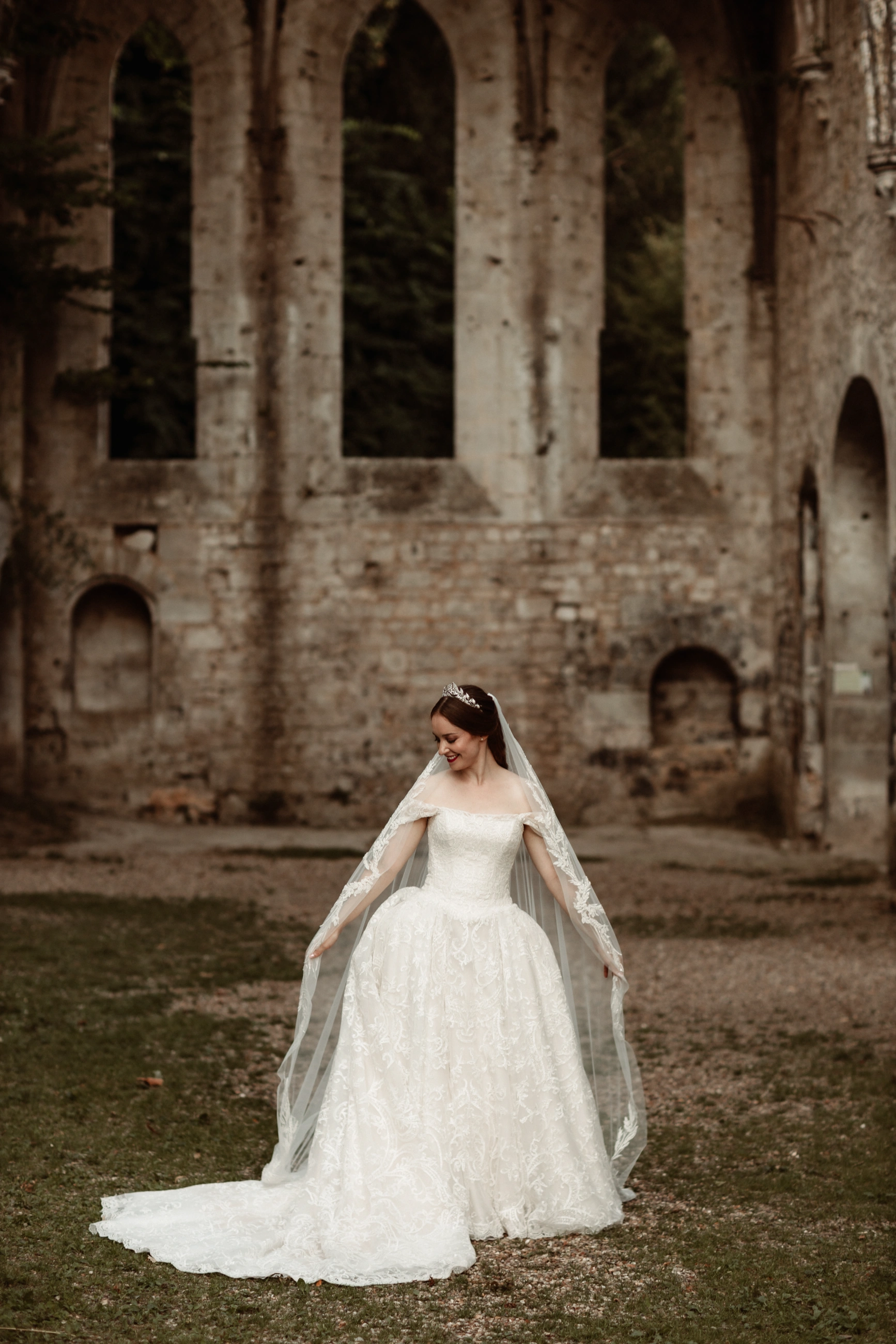 Custom ivory lace ballgown wedding dress, full-length view with her cathedral veil at the abbey ruins
