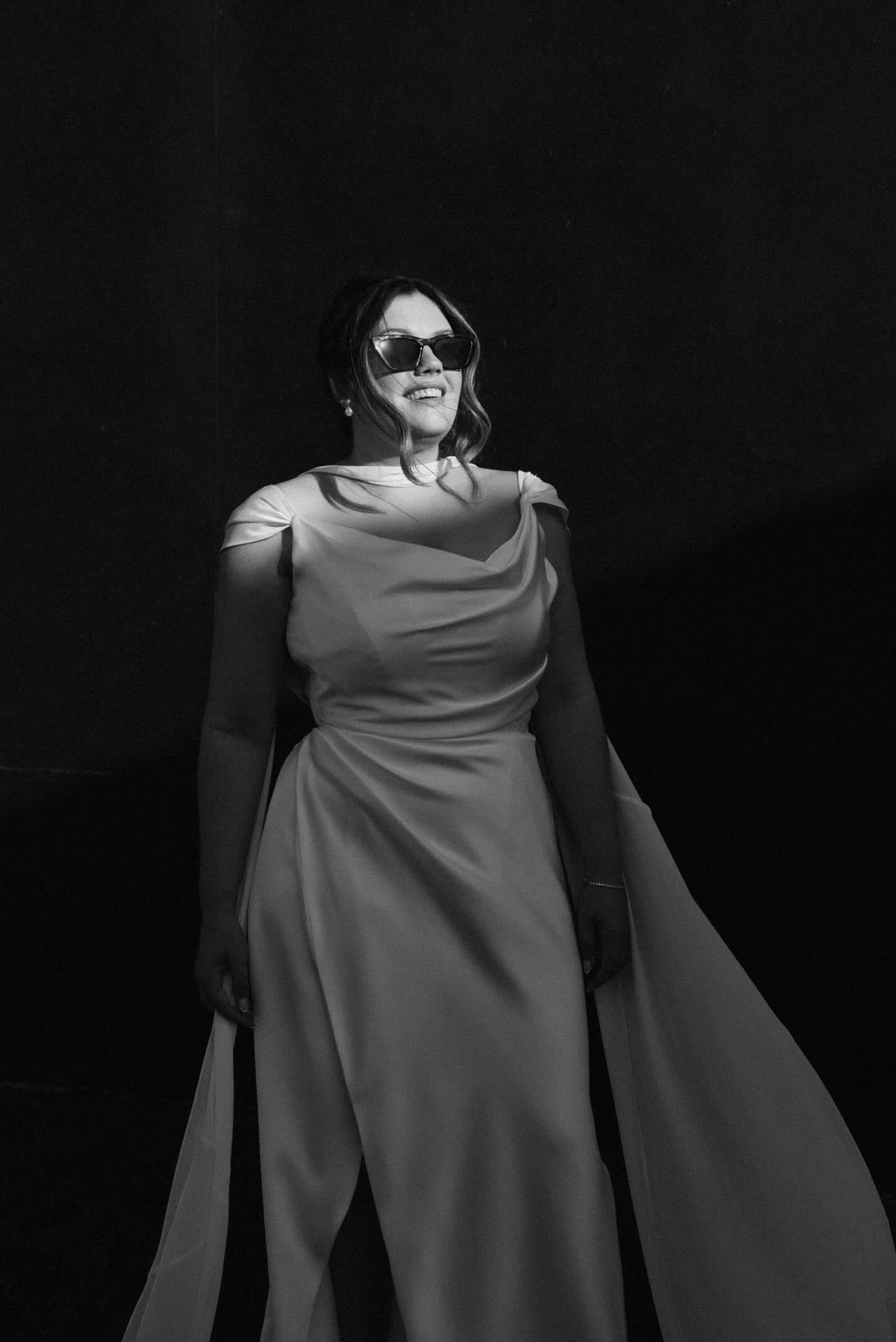 Custom bias-cut satin wedding dress with a chiffon cape, front view wearing sunglasses